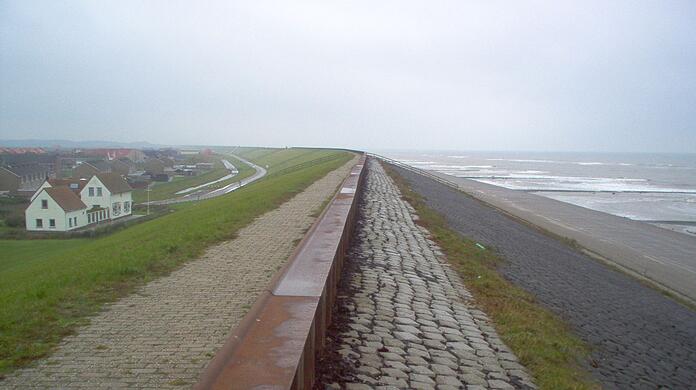 Ein Ort liegt an einem Deich hinter einem Strand in den Niederlanden.