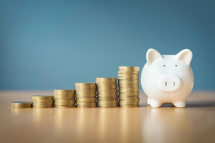 Rising stacks of coins alongside a piggy bank.