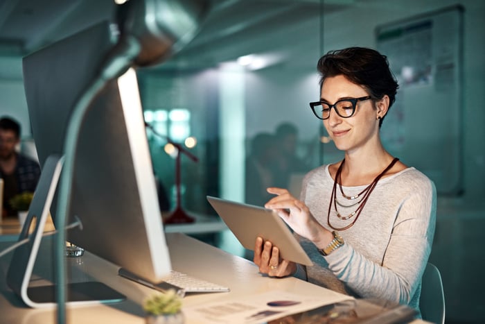 An investor sitting in an office looks at something on a tablet.