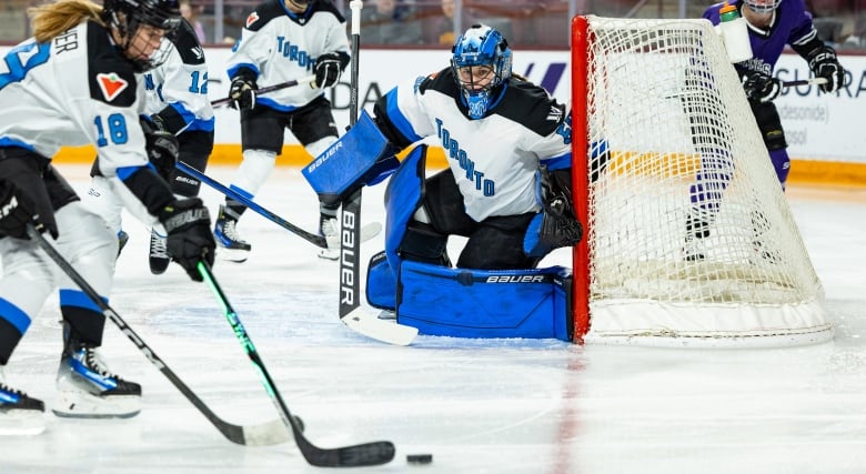 A goaltender in a Toronto jersey tracks the puck on the ice.