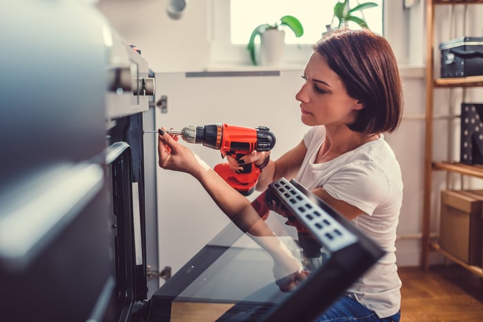 An individual with a power tool fixing the oven.