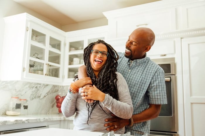 A middle-aged couple embraces happily in a kitchen.