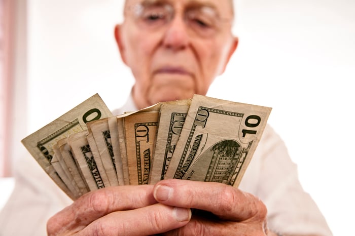 A person counting a fanned pile of assorted cash bills in their hands. 