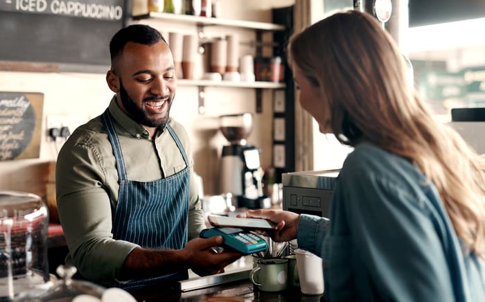 A person takes a card payment in a coffee shop.