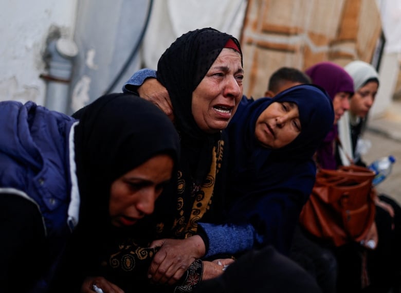 A woman is crying while being comforted by two other women. 