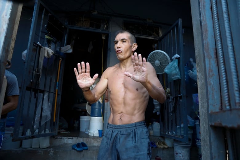 An inmate holds up his hands inside a prison cell.