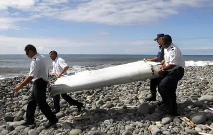 Frankreich, La Reunion: Techniker tragen ein Wrackteil, die Flügelklappe eines Flugzeugs, über einen Strand bei Saint-Andre de la Reunion. An diesem Freitag jährt sich zum zehnten Mal das Verschwinden der Boeing-Maschine, mit 239 Menschen an Bord.