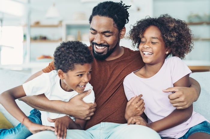 Smiling parent holding two children.