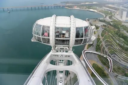 Blick aus der Höhe auf eine der gläsernen Kabinen des Riesenrads Bay Glory in Shenzen, China, in der mehrere Personen stehen