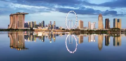 Blick auf die Bucht Marina Bay in Singapur mit ihren Wolkenkratzern und dem Riesenrad Singapore Flyer, das sich im Wasser spiegelt