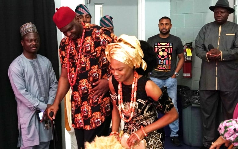 A man and woman wear traditional Nigerian clothing and beads.