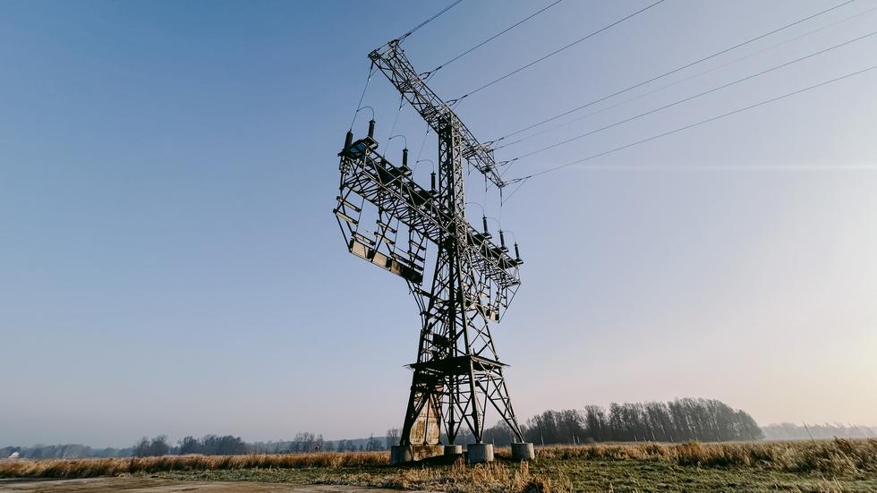 Tesla in Grünheide: Ein Strommast steht mit Brandspuren auf einem Feld nahe der Tesla-Autofabrik. In der Tesla-Autofabrik in Grünheide steht die Produktion wegen eines Stromausfalls nach einem Brandanschlag auf den Hochspannungsmast still.