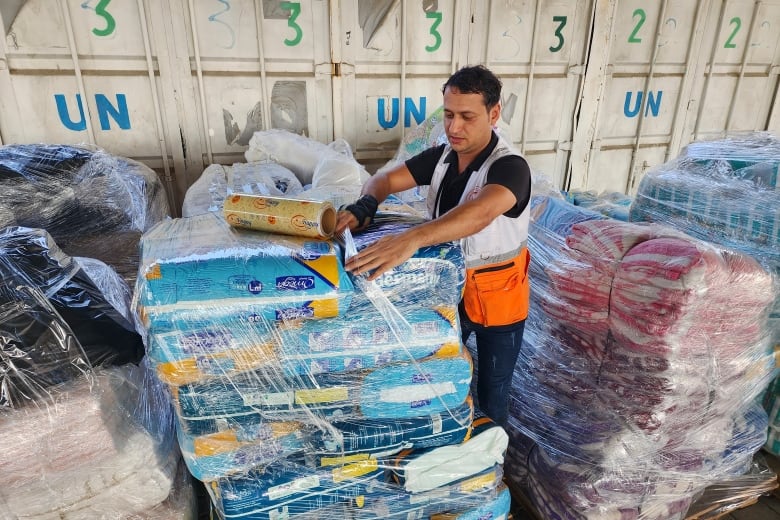 A warehouse worker wraps a pallet.