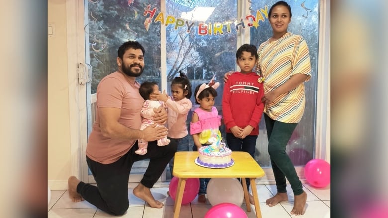 A photo of a family of six, with an older man on the right followed by three young daughters, a son and a mother.