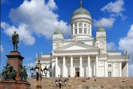 Blick auf den weißen Dom von Helsinki mit grüner Kuppel, zu dem eine Treppe führt, davor eine Statue