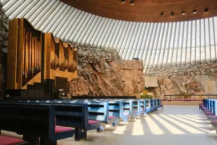 Blick in den Innenraum der Temppeliaukio Kirche in Helsinki, die in den Felsen geschlagen wurde, mit Orgel und schmalen Fenstern unter dem Dach