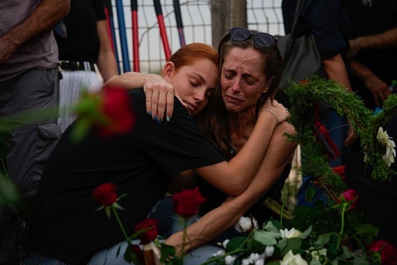 Mourners embrace during the funeral of Meni and Ayelet Godard, in Kibbutz Palmachim, Israel Sunday, Oct. 29, 2023. The Israeli couple were killed by Hamas militants on Oct. 7, in Kibbutz Be'eri near the border with the Gaza Strip. More than 1,400 people were killed and some 220 captured in an unprecedented, multi-front attack on Israel by the militant group that rules Gaza.