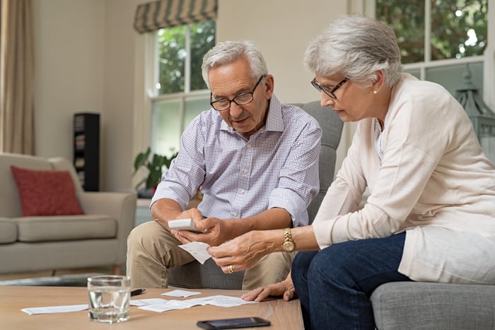 Two adults sitting together looking at financial paperwork. 