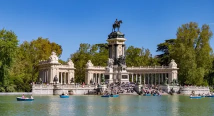 See mit kleinen Booten in einem Teich und riesiges Denkmal im Hintergrund.