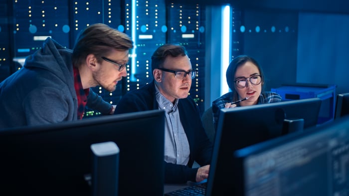 Three IT professionals looking at a monitor.