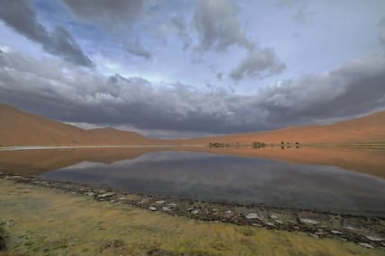 Blick über den Yinderitu-See zu den sich erhebenden Sanddünen von Badain Jaran.