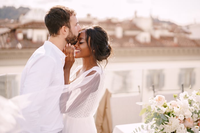 Two people wearing white embrace.