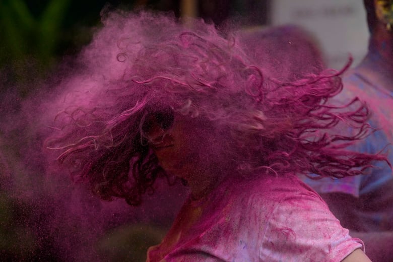 A girl shakes her head, which was covered with fuscia powder.