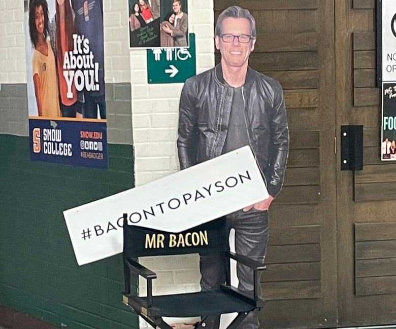 A cardboard cut out of Kevin Bacon stands in a hall.