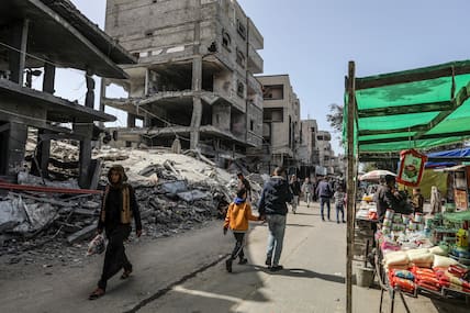 Vertriebene Palästinenser gehen an zerstörten Gebäuden im Gazastreifen vorüber.