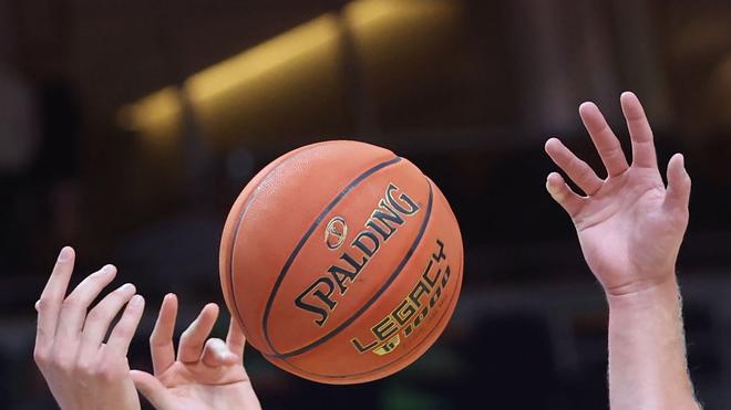 Basketball: Spieler greifen nach einem Basketball.