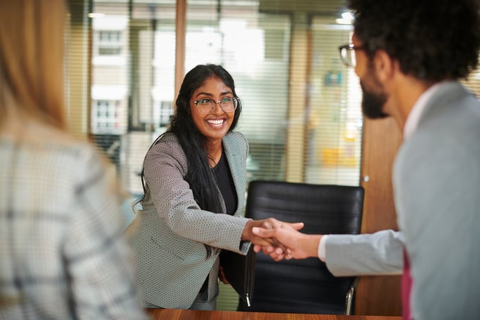 Smiling businessperson shaking hands with someone.