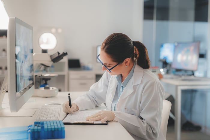 Person in lab taking notes in front of computer.