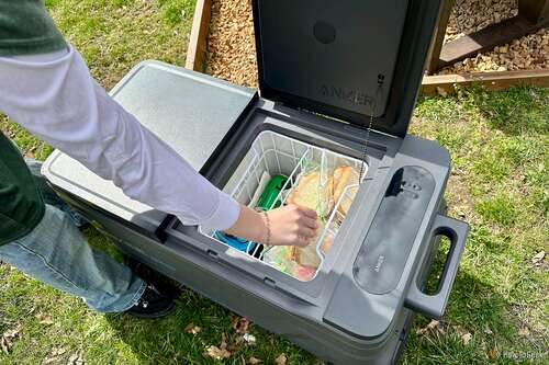 Removing sandwiches from an Anker EverFrost Dual-Zone Powered Cooler 50 on grass