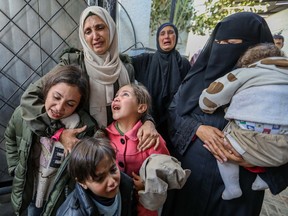 People cry as they mourn while receiving the dead bodies of victims of an Israeli strike on Saturday, March 2, 2024, in Rafah, Gaza.