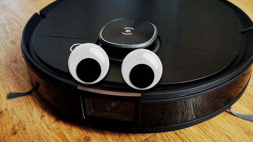 A robot vacuum with goo-goo eyes attached to it.