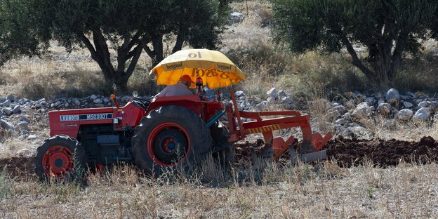 Eine Person fährt mit einem Traktor über ein Feld.