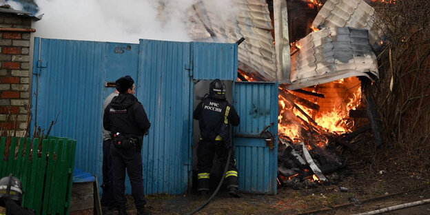 Ein Feuer brennt, zwei Menschen löschen es