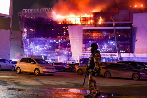 Ein Mitglied der OMON-Sonderpolizeieinheit steht nach einer Massenerschießung durch mehrere nicht identifizierte Bewaffnete vor der Crocus-Hall in der Stadt Krasnogorsk in der Nähe von Moskau. Die Evakuierung ist im Gange. Foto: picture alliance/dpa/TASS | Mikhail Tereshchenko