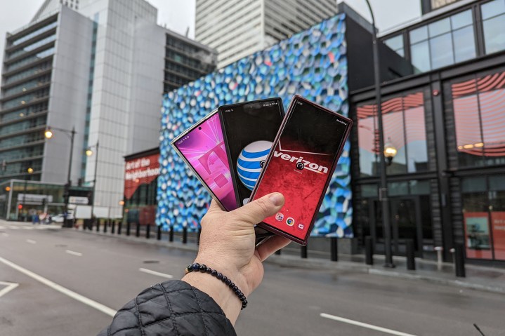 Hold holding three phones from three different carriers.