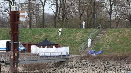 Polizisten untersuchen am Fundort einer Leiche die Umgebung. Am Hafen in Köln ist am Sonntagmorgen ein 15-Jähriger tot an einer Landzunge gefunden worden.