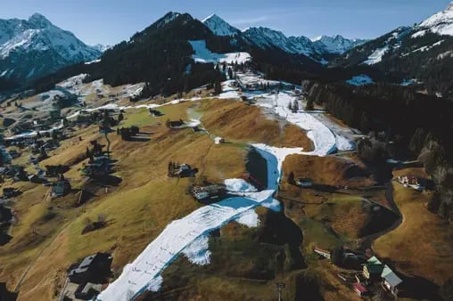 dpatopbilder - 30.12.2022, Österreich, Riezlern: Freizeitsportler fahren auf einer Kunstschneepiste Schnee. In vielen niedrig gelegenen Skigebieten sieht es zur Zeit schlecht aus mit dem Wintersport. Bei Temperaturen um die zehn Grad ist auch die Produktion von Kunstschnee nicht mehr möglich. Foto: Expa/ Jfk/APA/dpa +++ dpa-Bildfunk +++