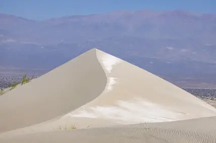 Steile helle Sanddüne bei Fiambalá in Argentinien, dahinter eine karge Berglandschaft