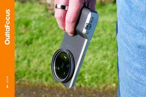 Promotional image for OuttaFocus. A person holding the Xiaomi 14 Ultra, with the Photography Kit fitted.