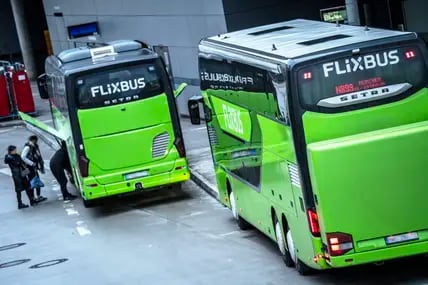 Menschen packen ihre Taschen in einen parkenden Flixbus.