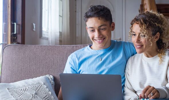 Parent and teenager using laptop at home