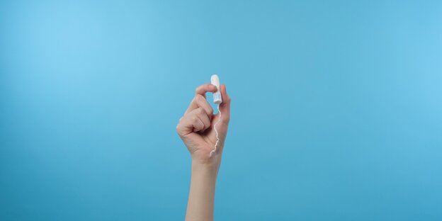 Eine Hand vor blauem Hintergrund hät einen Tampon