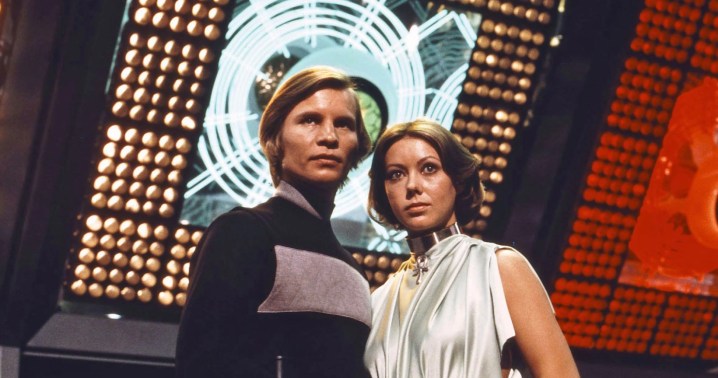 A man and a woman stand in a control room in Logan's Run.