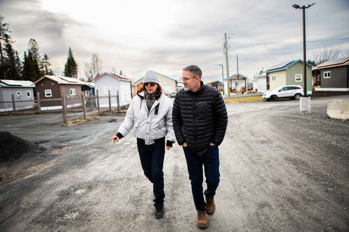 Two men on a gravel path walking between tiny homes