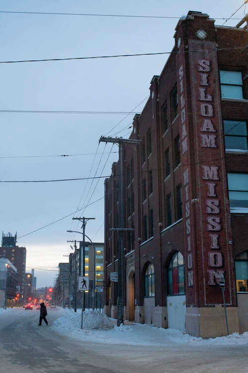 A picture of a brick multi-storey building with words on the side: SILOAM MISSION