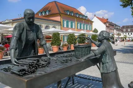 In der Spargelstadt Schwetzingen steht eine Spargelfrau-Statue vor dem Schlosseingang.